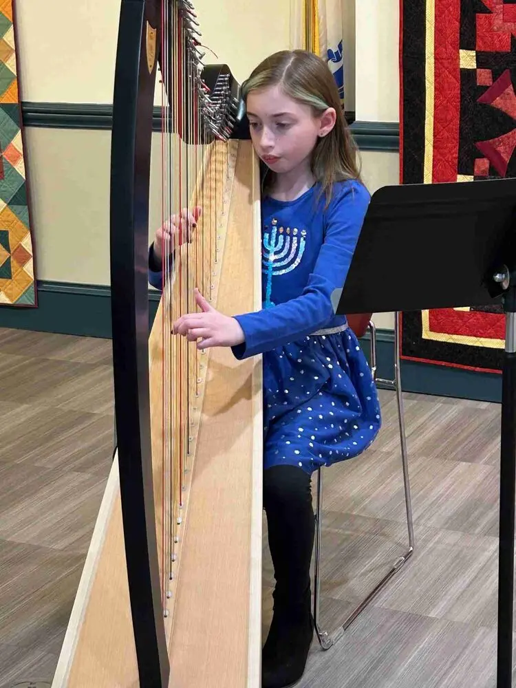 A talented Allegro Music School student enchants the audience with a mesmerizing harp performance at the Winter Recital.