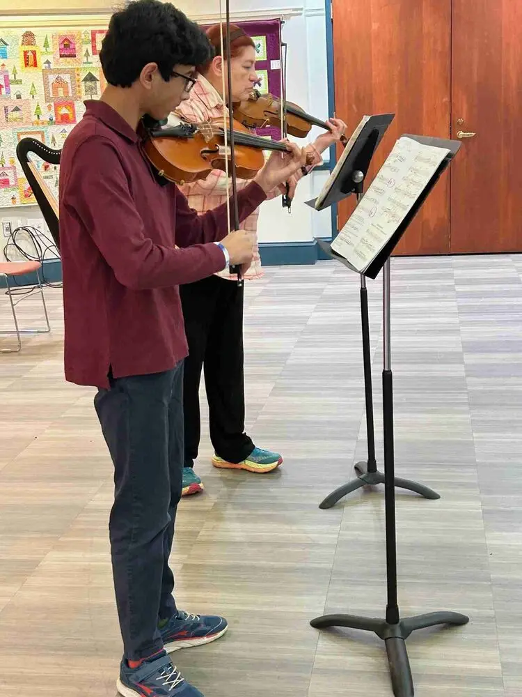 An Allegro Music School student performs a violin duet with his teacher, showcasing harmony and skill at the Winter Recital.