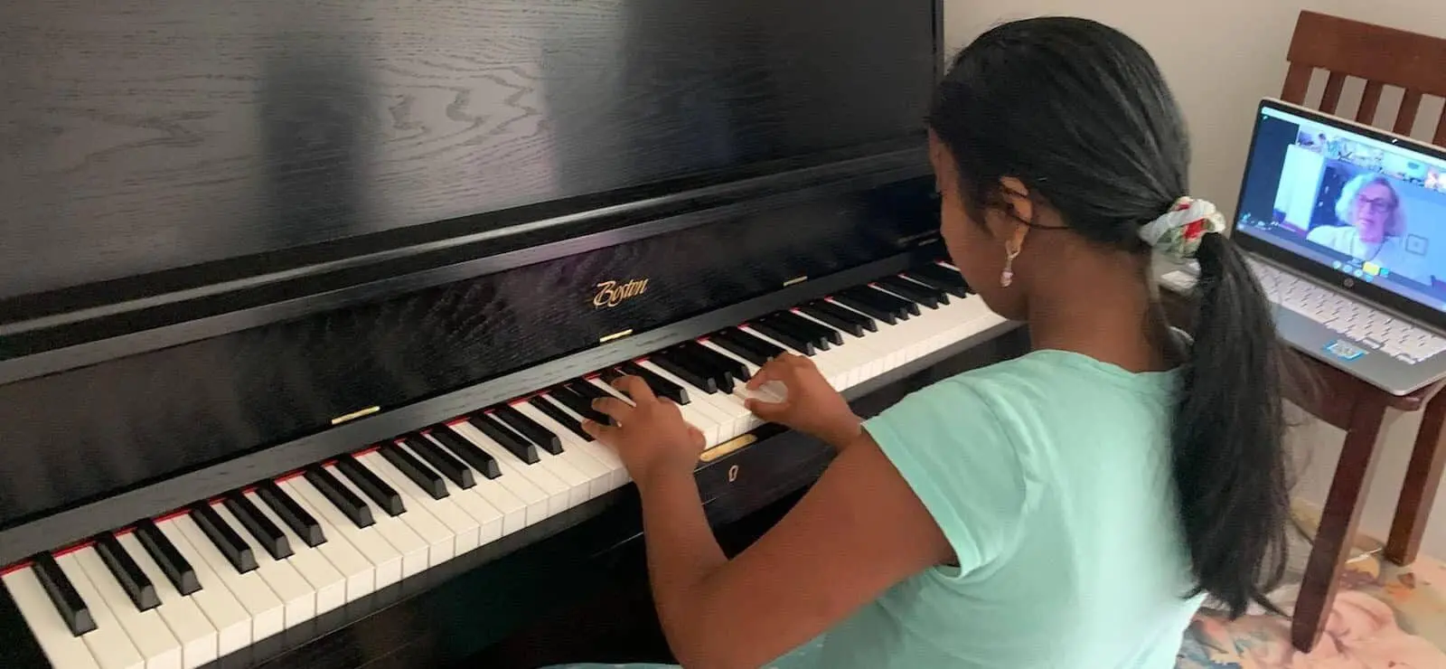 An Allegro Music School Student playing a piano next to an instructor on the computer