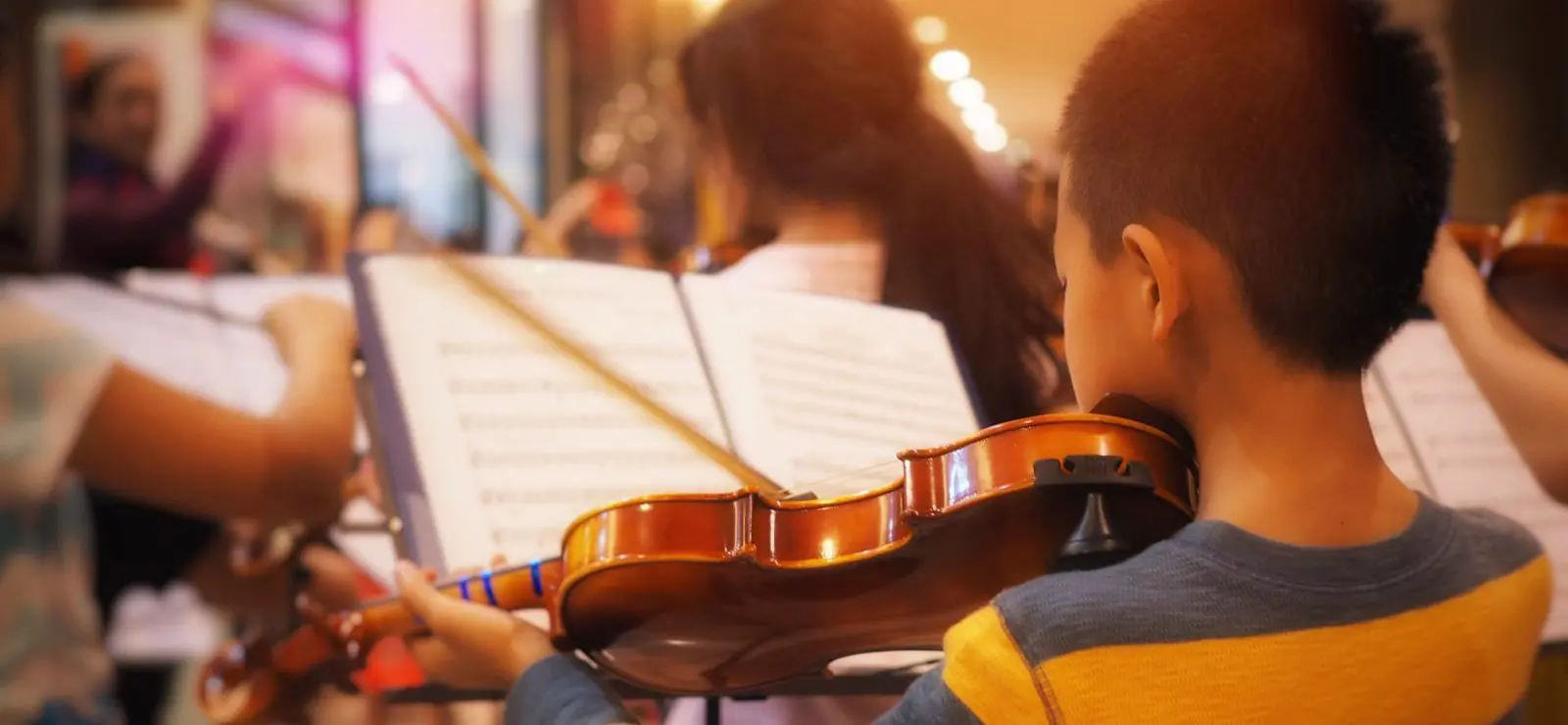 Young violinist practicing with orchestra band.